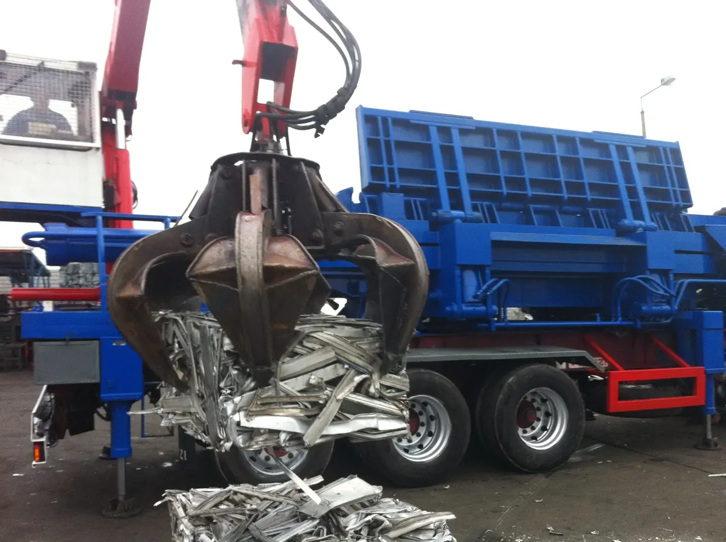 Grab crane loading scrap into a container at the yard